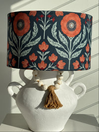 Floral-patterned lampshade on a white surface with a decorative vase.