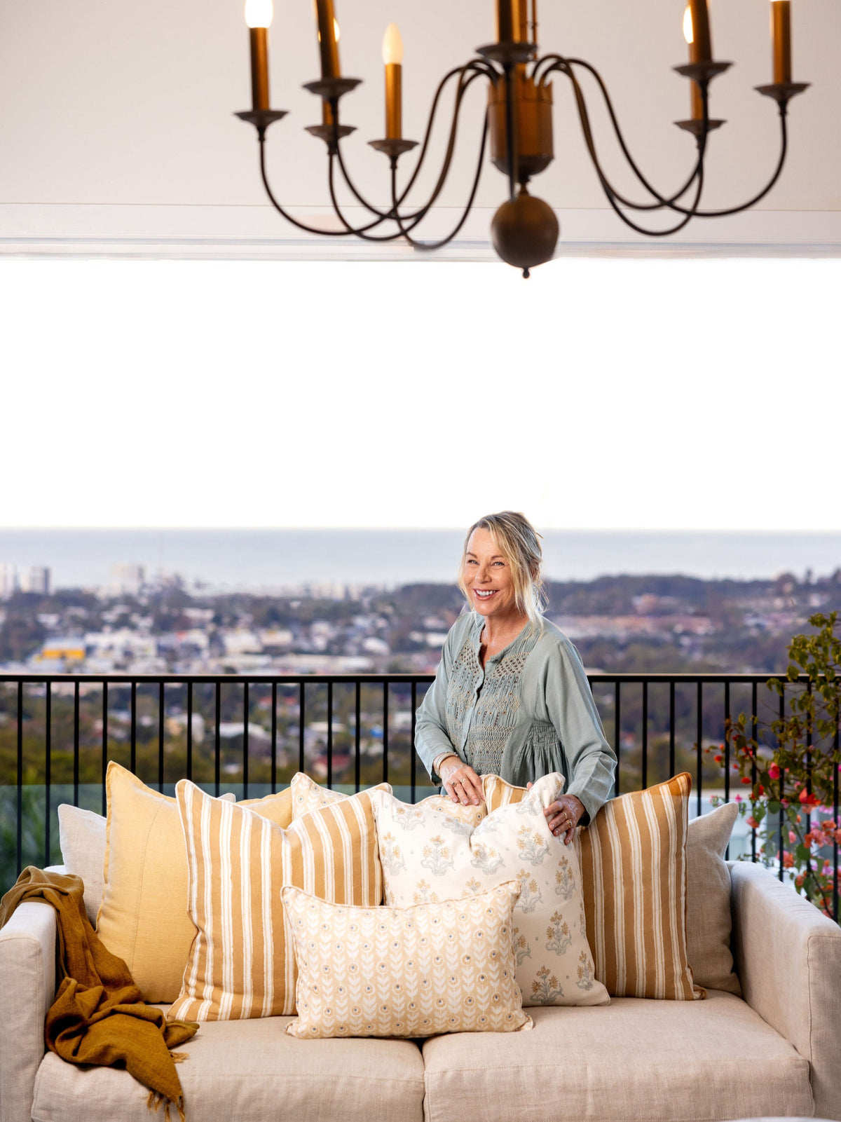 Woman arranging pillows on a couch with a scenic view in the background