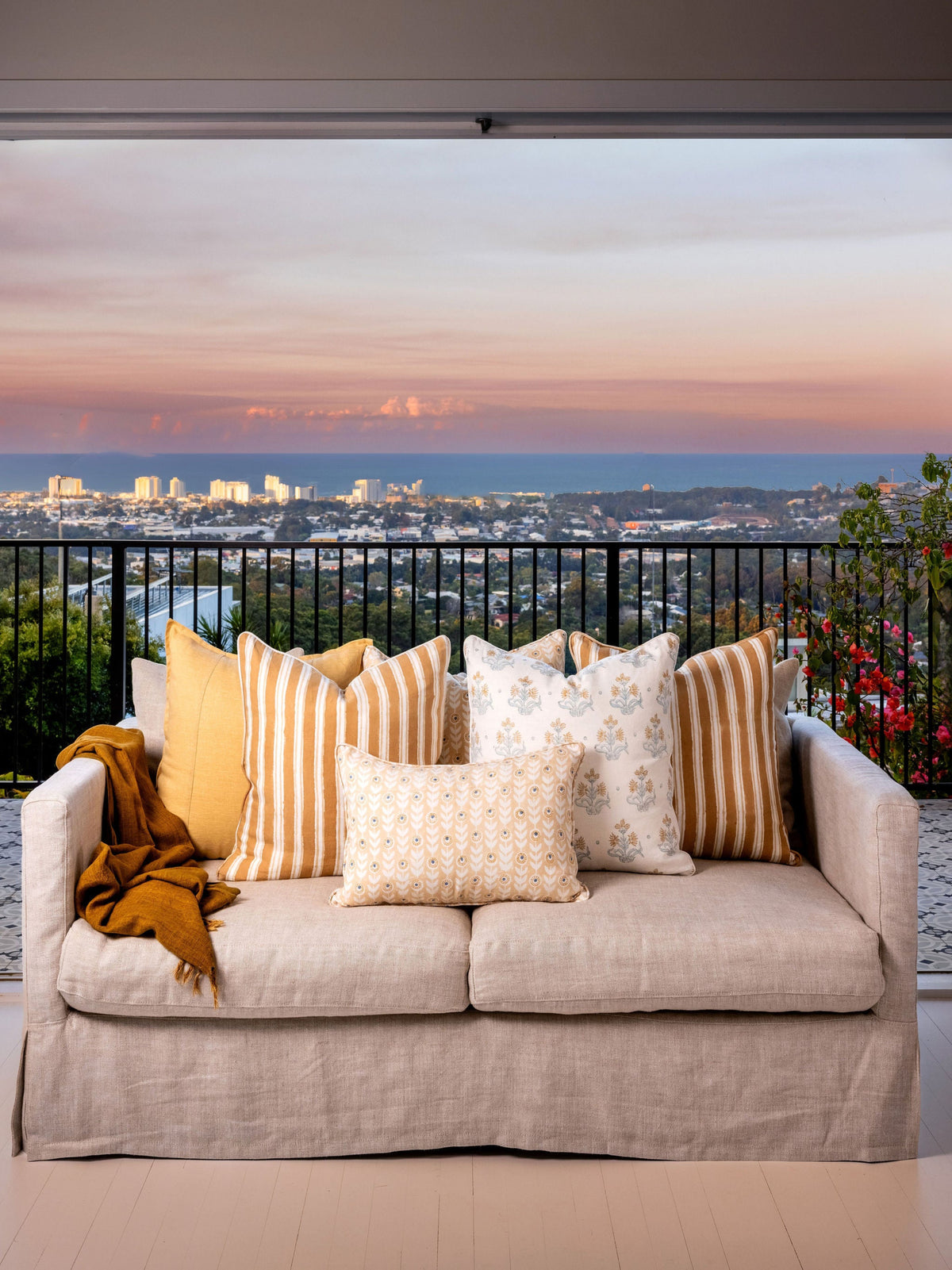 Beige sofa with decorative pillows and a blanket against a cityscape backdrop
