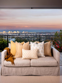 Beige sofa with decorative pillows and a blanket against a cityscape backdrop