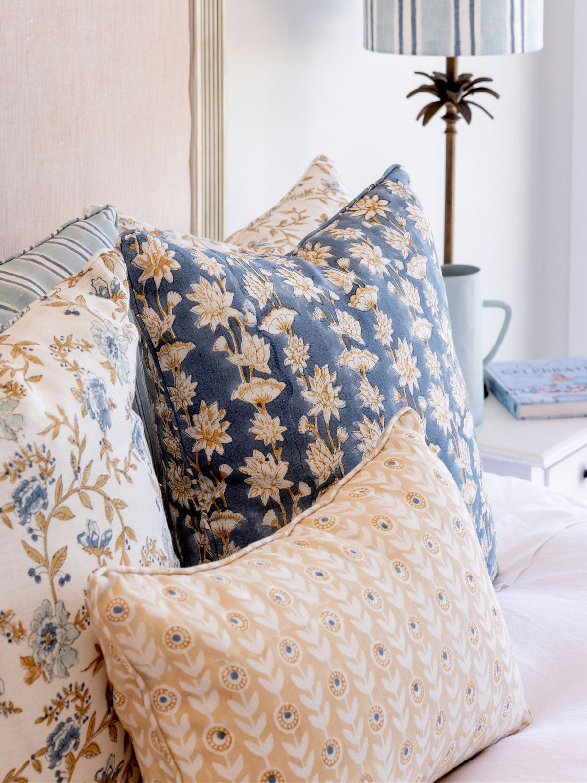 Decorative pillows with floral patterns on a bed in a bedroom setting.
