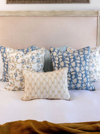 Decorative pillows on a bed with a painting in the background