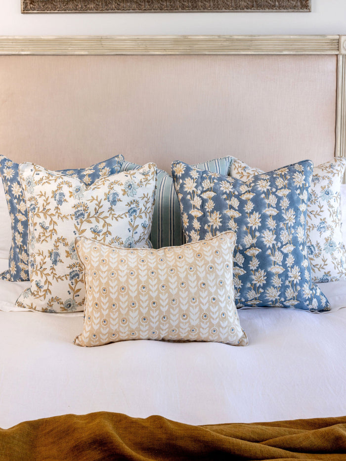 Decorative pillows on a bed with a painting in the background