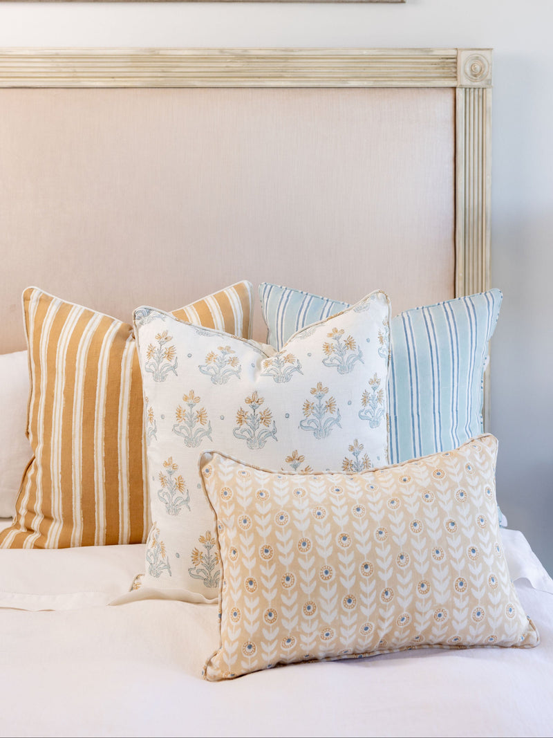 Decorative pillows on a bed with a painting in the background