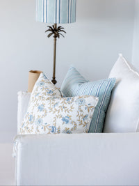 Decorative pillows on a sofa with a lamp in the background