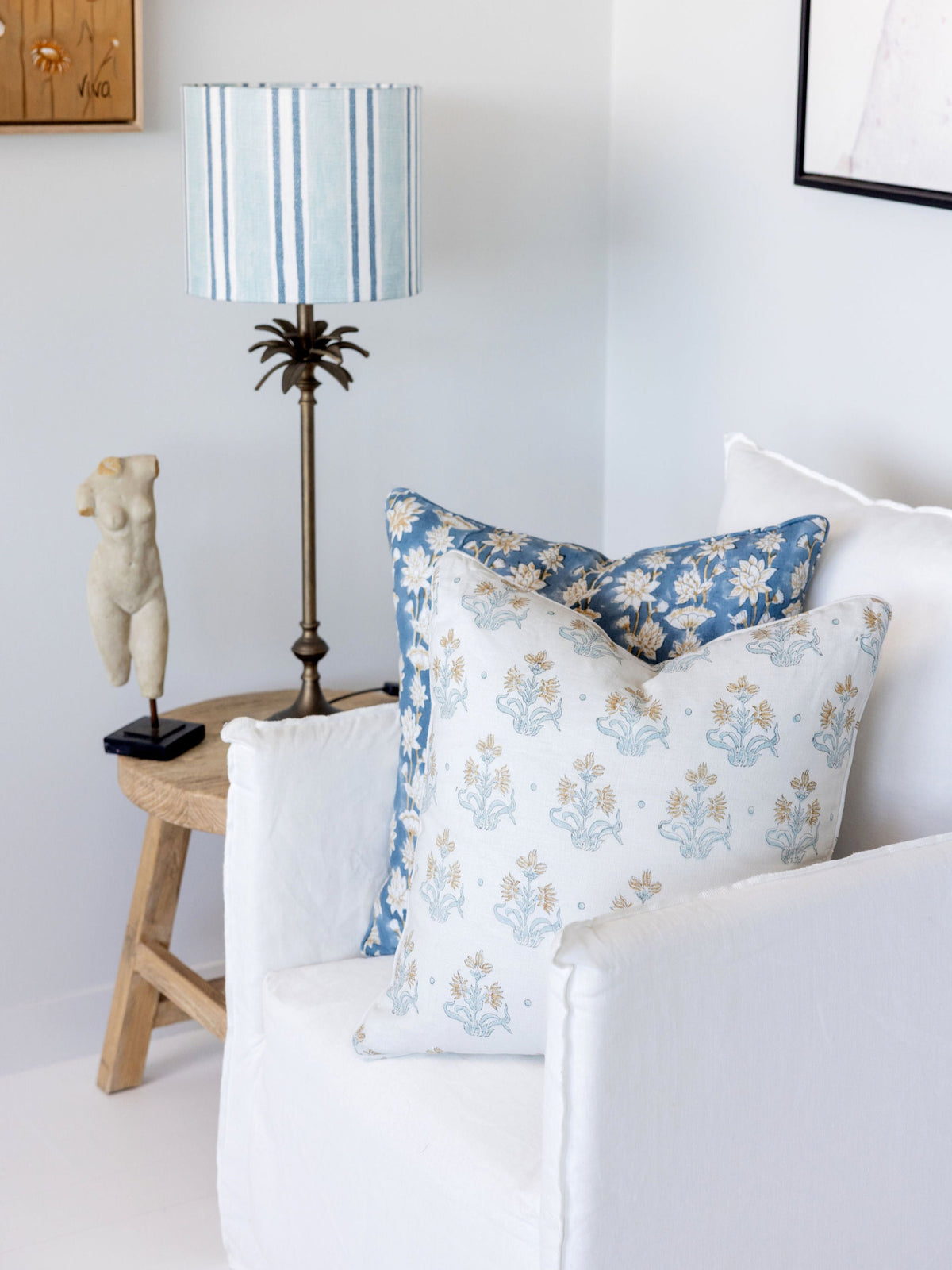 Decorative pillows on a sofa with a lamp and small table in the background.