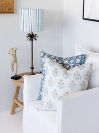 Decorative pillows on a sofa with a lamp and small table in the background.