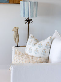 Decorative pillows on a sofa with a striped lamp in the background