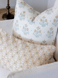 Two patterned pillows on a white sofa with a lamp in the background.