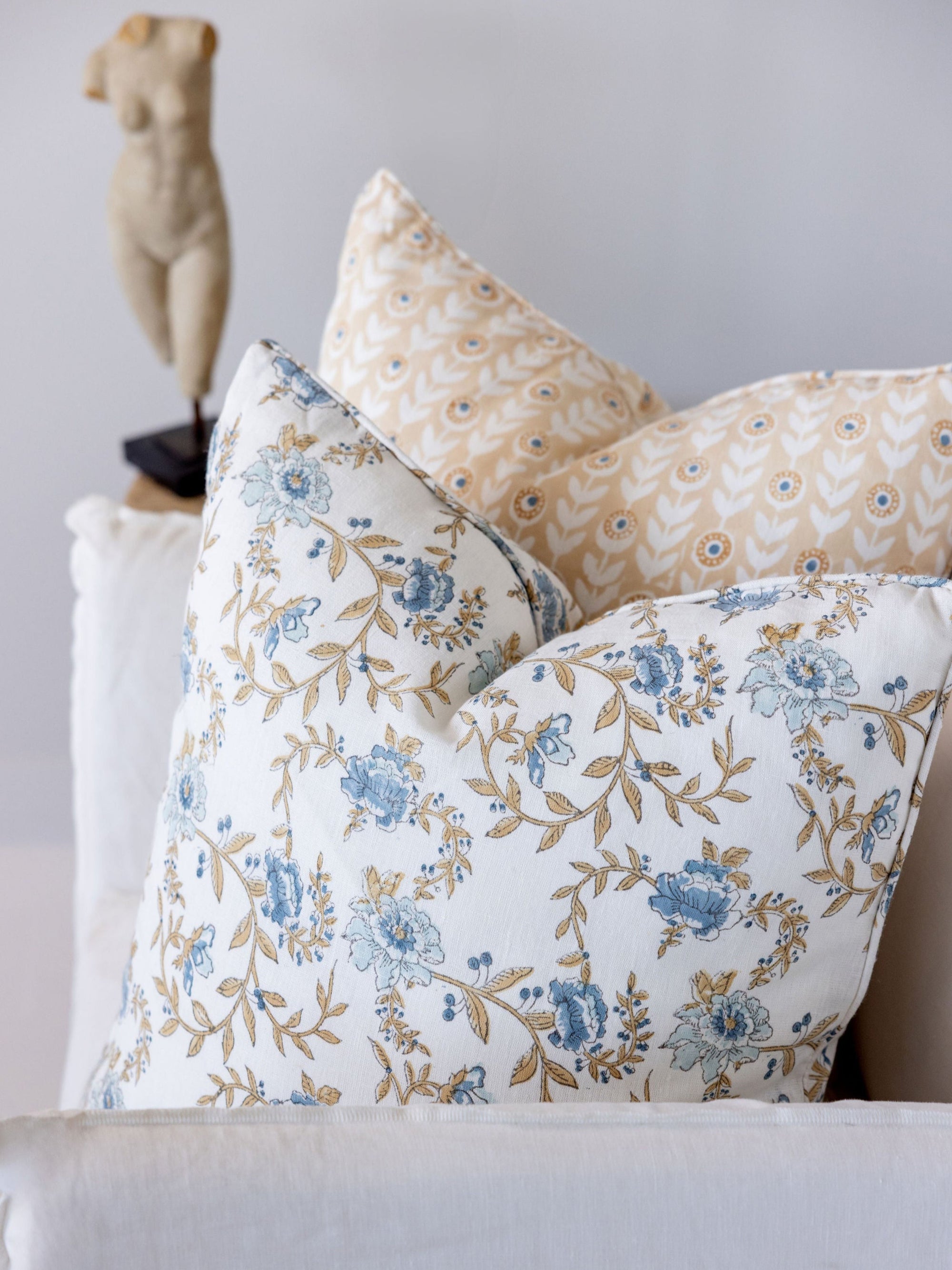 Floral patterned pillows on a sofa with a neutral background