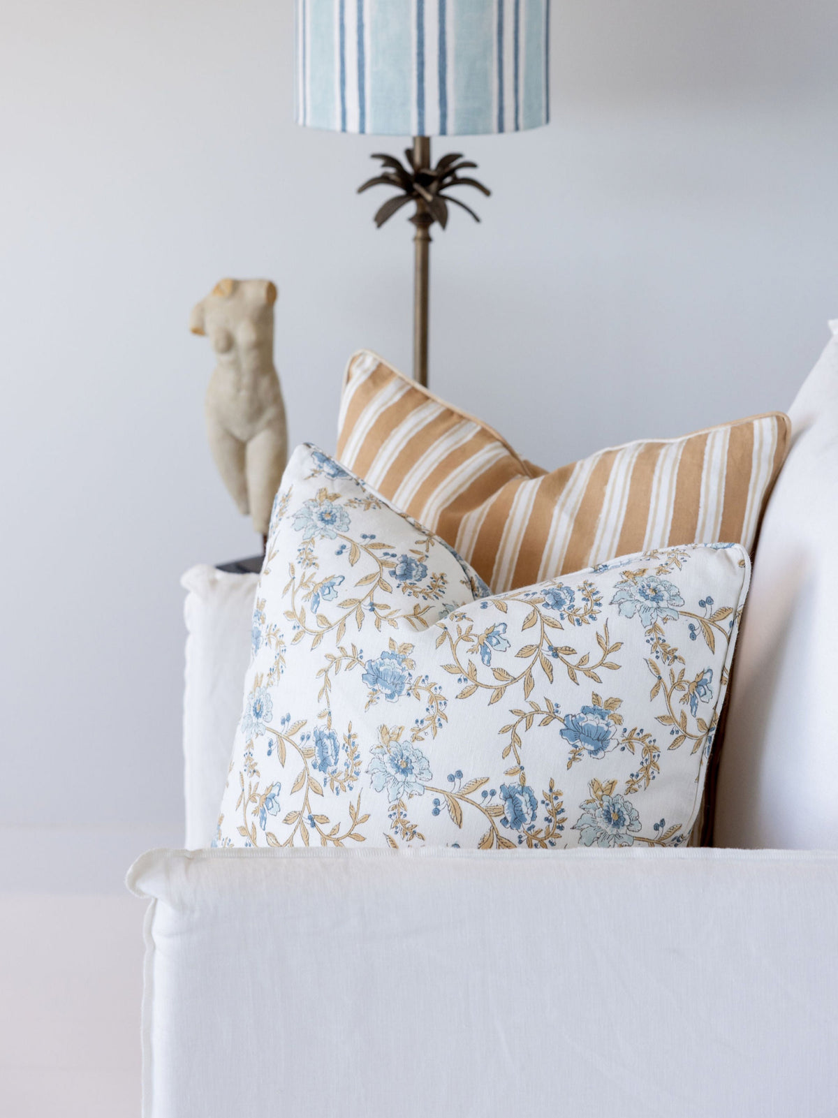 Decorative pillows on a sofa with a lamp and statue in the background