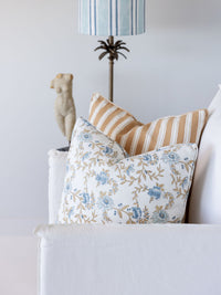 Decorative pillows on a sofa with a lamp and statue in the background