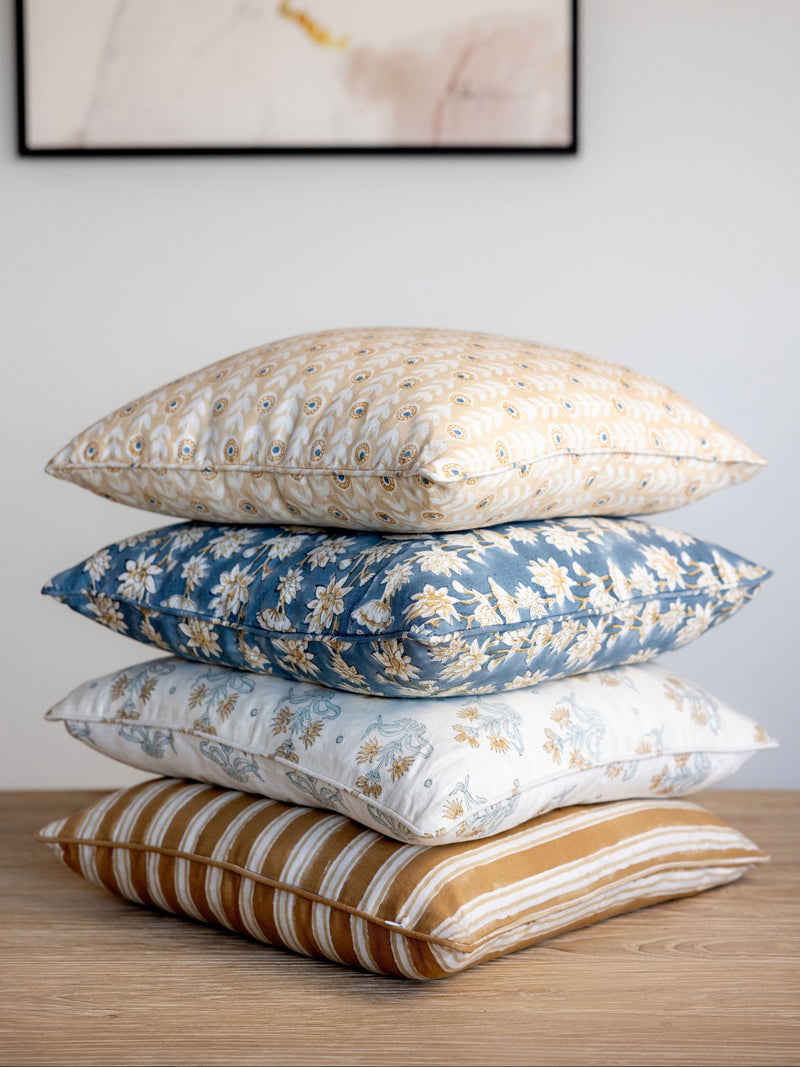 Stack of decorative pillows on a wooden surface with a neutral background