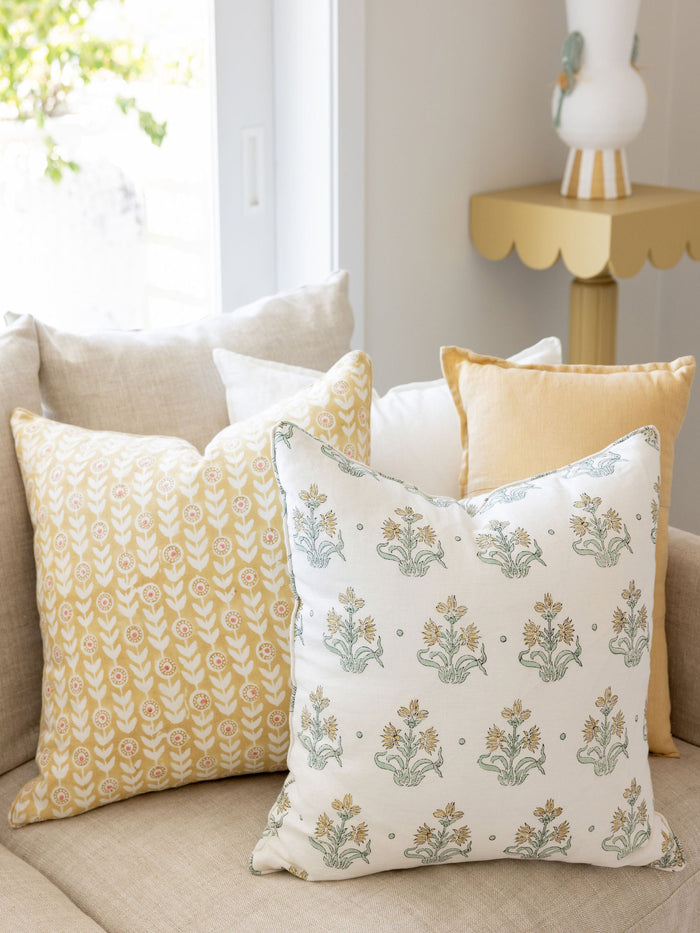 Decorative pillows on a beige sofa with a side table in the background