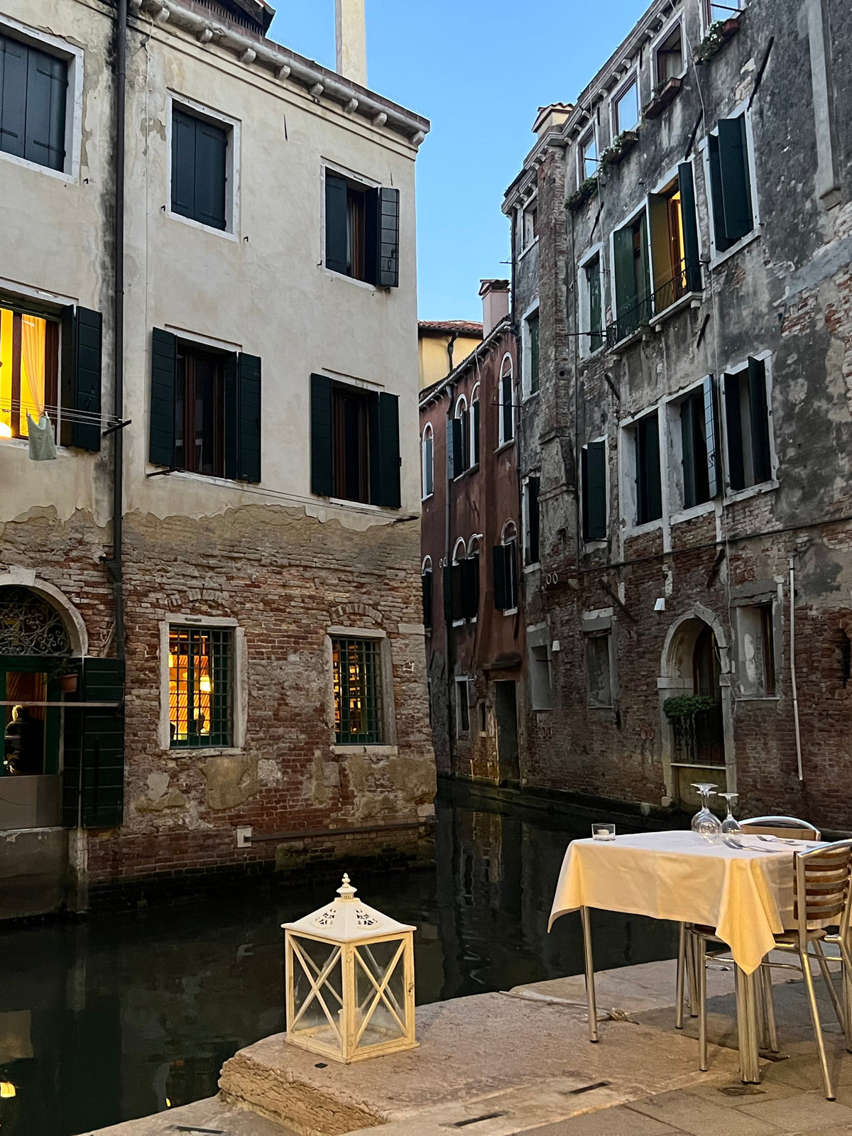 Venetian canal with historic buildings and a table by the water