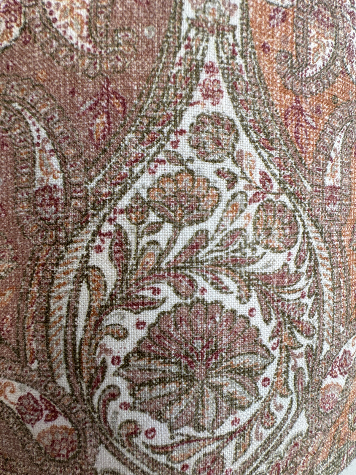 Close-up of intricate paisley pattern on fabric with earthy tones.