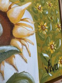 Close-up of a sunflower with a green background featuring more flowers, and the word 'Viva'.