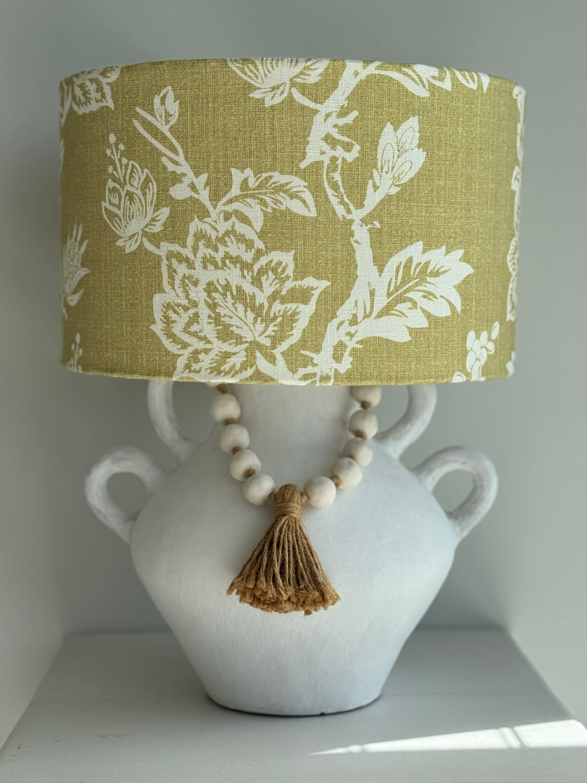 Lamp with floral-patterned shade on a white vase with beads and tassel