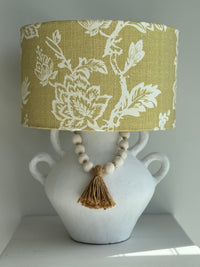 Lamp with floral-patterned shade on a white vase with beads and tassel