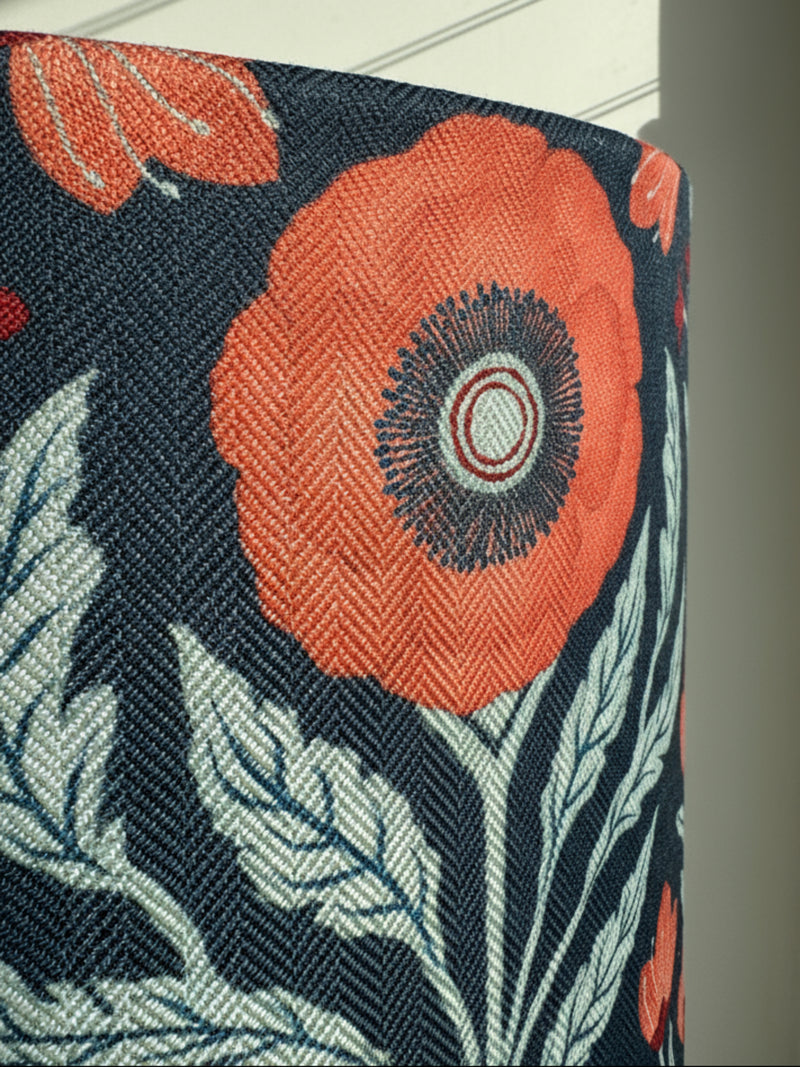 Close-up of a floral patterned fabric lampshade with orange flowers on a dark blue background.