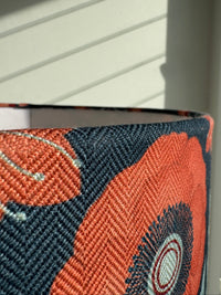 Close-up of a patterned fabric lampshade with orange and blue design on a white background