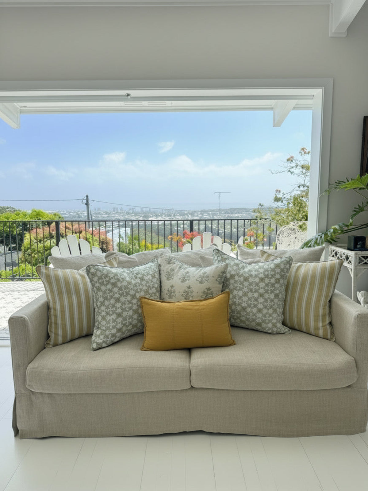 Beige sofa with patterned and solid cushions in a room with large windows showing a scenic view.