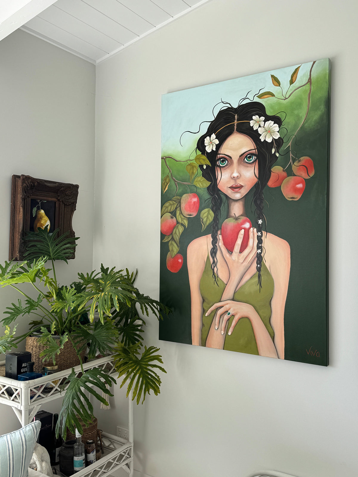 Canvas print of a woman holding an apple in a room with plants and a white wall.