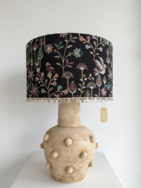 Decorative lamp with floral patterned shade and textured base on a white background