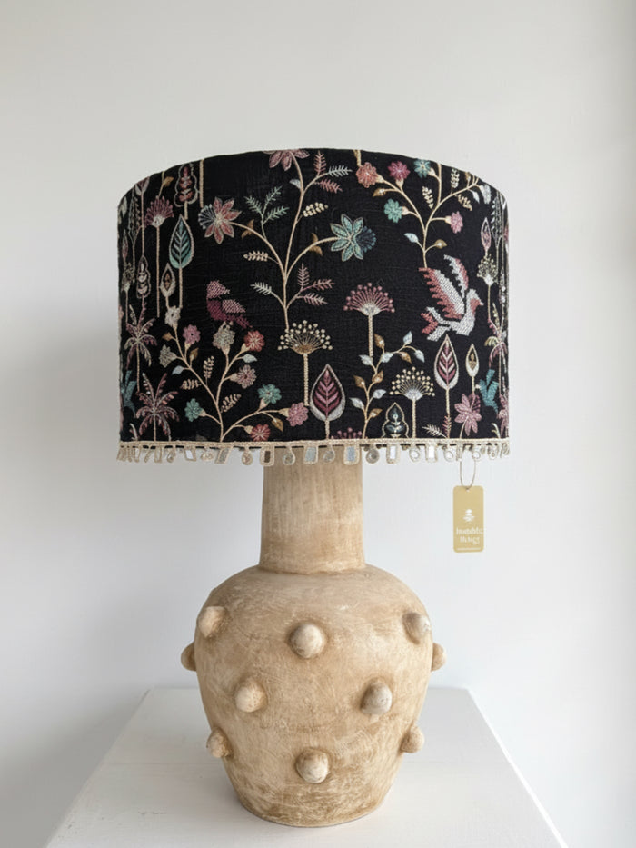 Decorative lamp with floral patterned shade and textured base on a white background