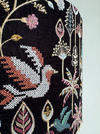 Embroidered fabric with a phoenix design and floral elements on a black background
