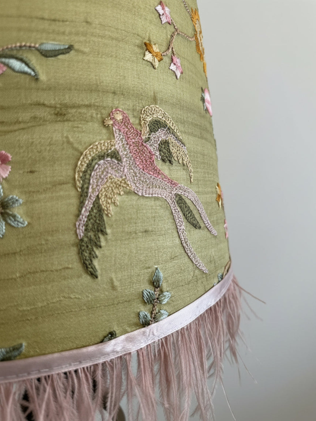 Embroidered fabric with a bird design and fringes on a plain background
