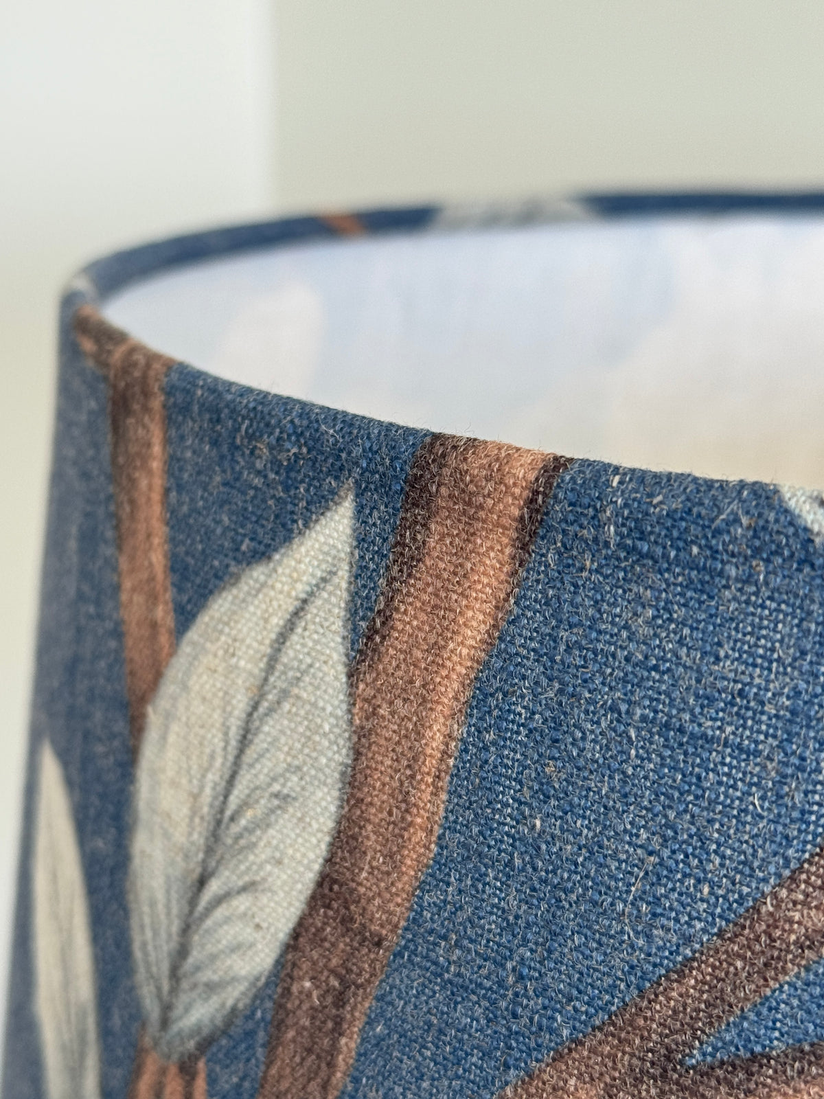 Close-up of a cylindrical container with leaf pattern on a blue background