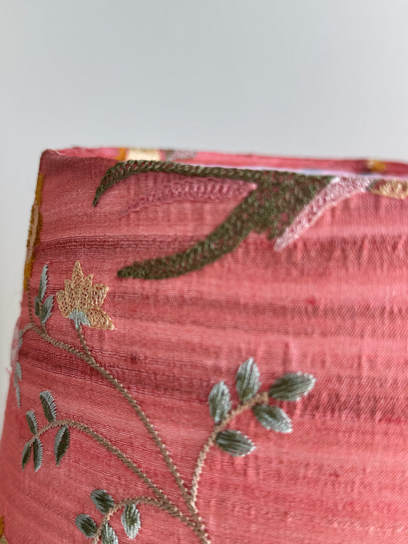 Close-up of a pink fabric with floral embroidery on a white background