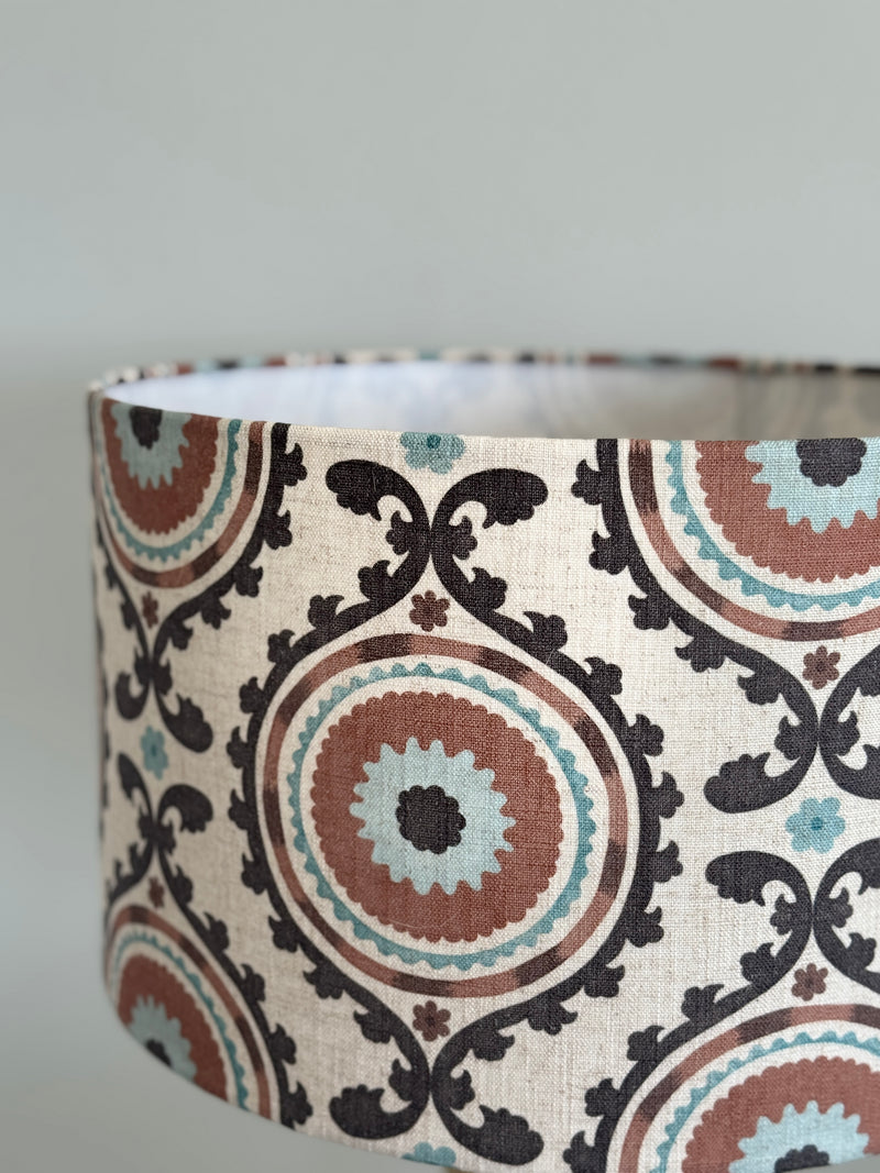 Patterned lampshade with brown, blue, and beige design on a plain background