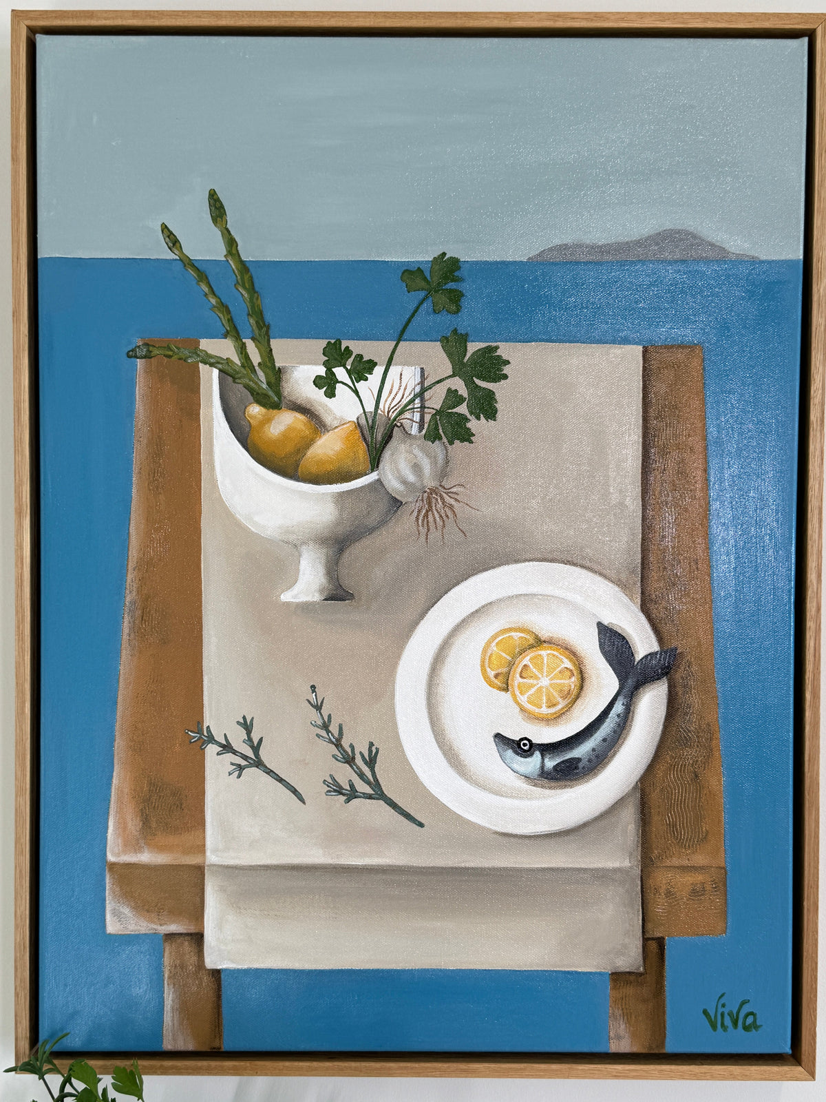 Framed artwork of a still life with fish, lemon, and herbs on a blue background