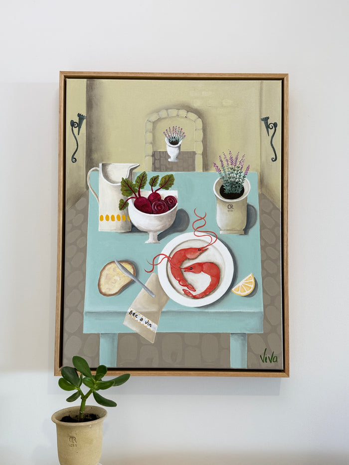 Framed artwork of a table setting with food and decor on a white wall.