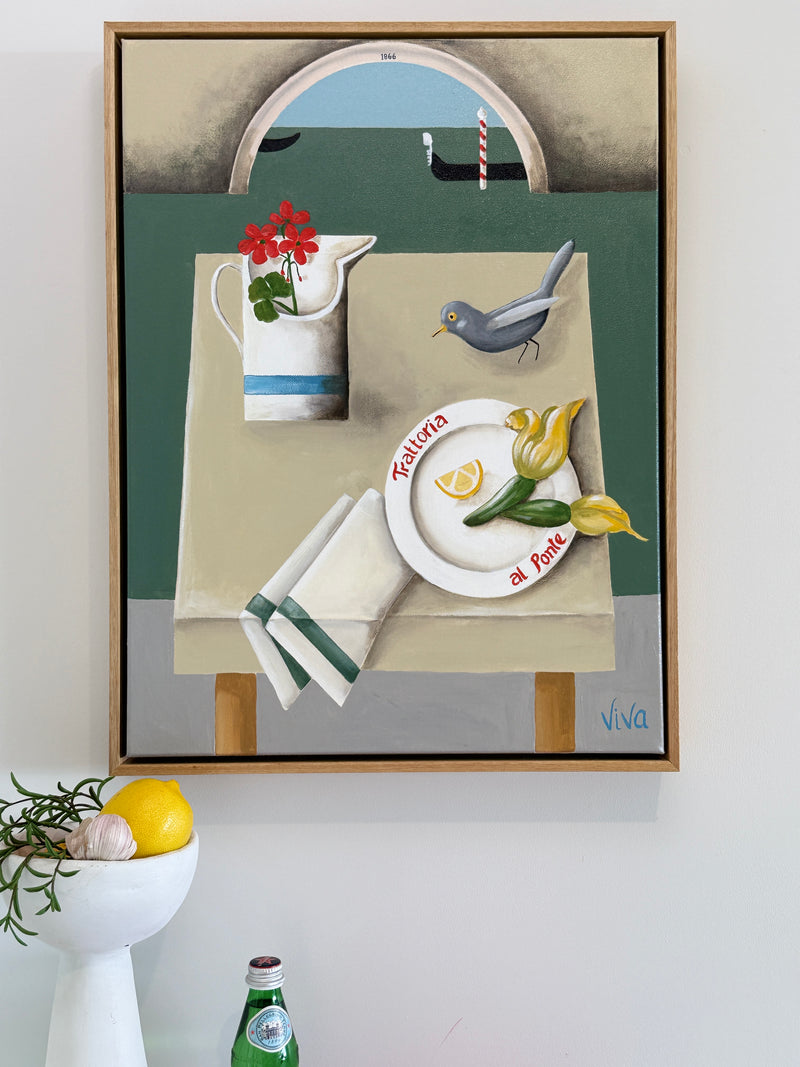 Framed artwork of a still life scene with a table, flowers, and a bird on a white wall.