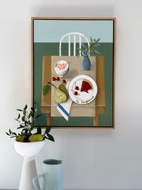 Framed artwork of a still life scene with a table setting on a wall.