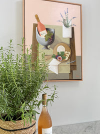 Bottle of white wine on a surface with a framed painting in the background