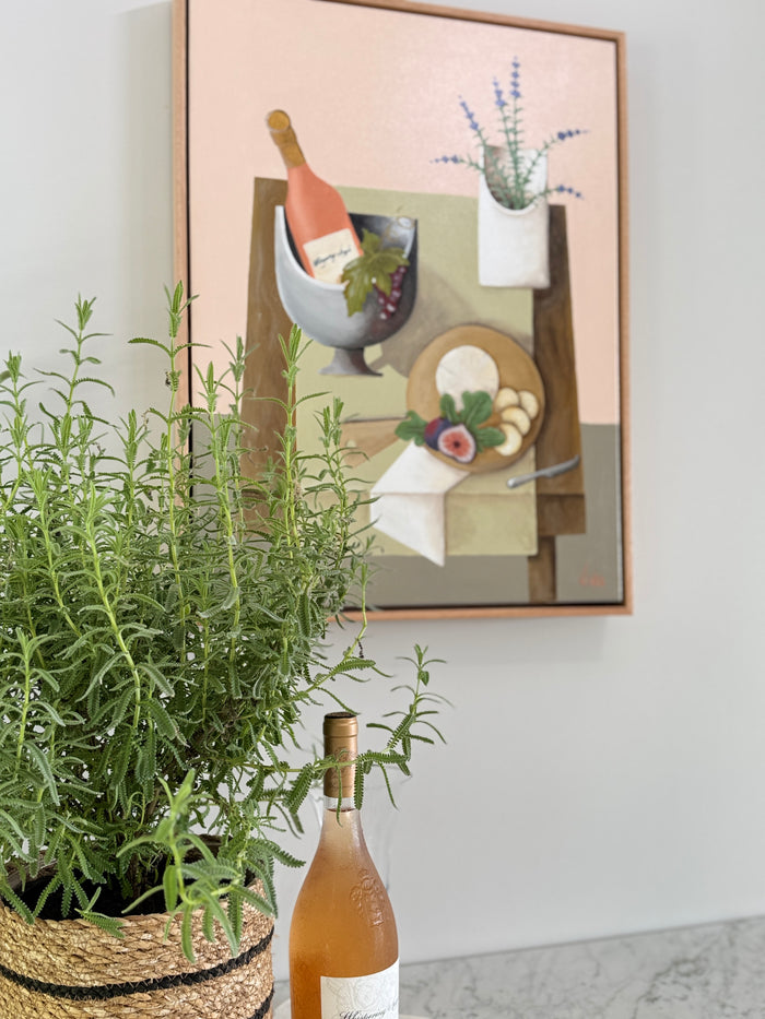 Bottle of white wine on a surface with a framed painting in the background