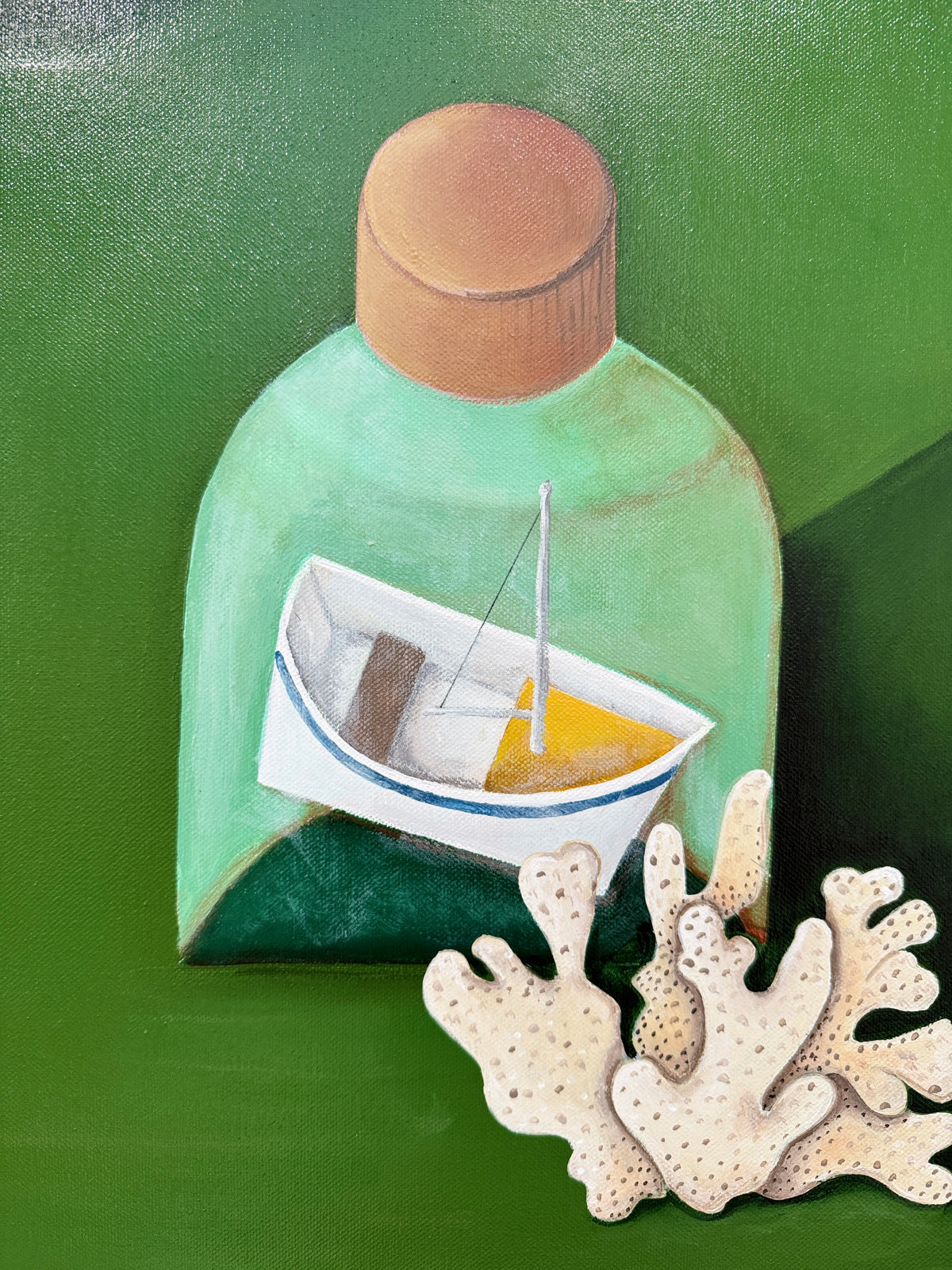 Decorative wall art with a bottle containing a toy boat on a green background