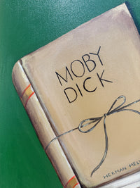 Book titled 'Moby Dick' with a decorative bow on a green background