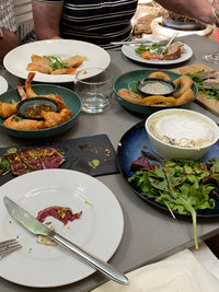 Dining table with plates of food, cutlery, and drinks in a casual setting.