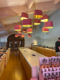 Modern chandelier with red and yellow design in a room with wooden floors and shelves.