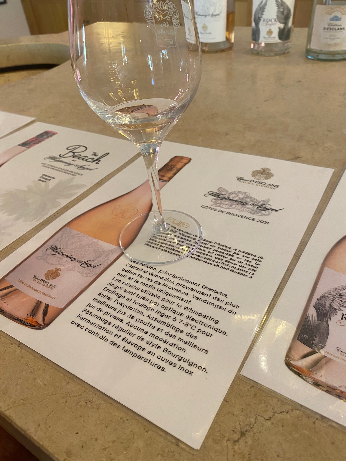 Wine glass being filled with white wine on a table with a wine label and bottle in the background.