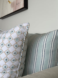 Two pillows, one with a geometric pattern and the other with stripes, on a neutral background.
