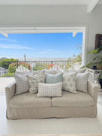 Beige sofa with patterned cushions in a room with a door leading outside.