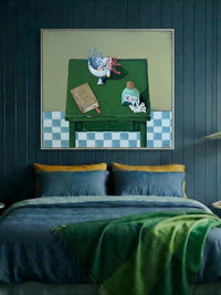 Bedroom with blue walls, a bed with green and blue bedding, and a framed artwork above the bed.
